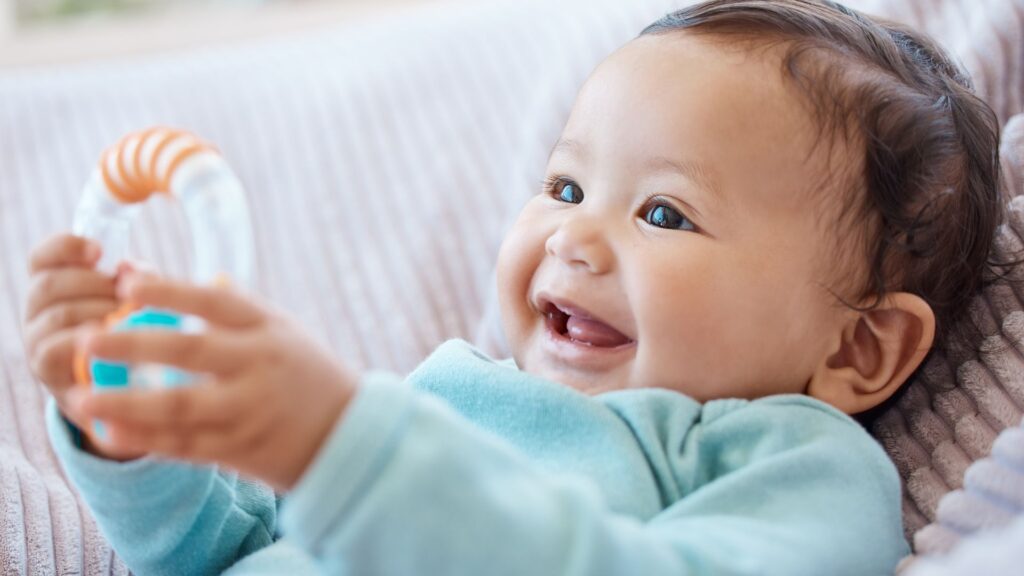 Első babaszoba berendezése: kisbaba mosolyog a babaágyon fekve.